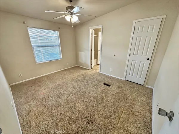 an empty room with windows and fan