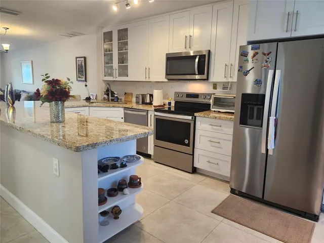 a large kitchen with stainless steel appliances lots of counter space and windows