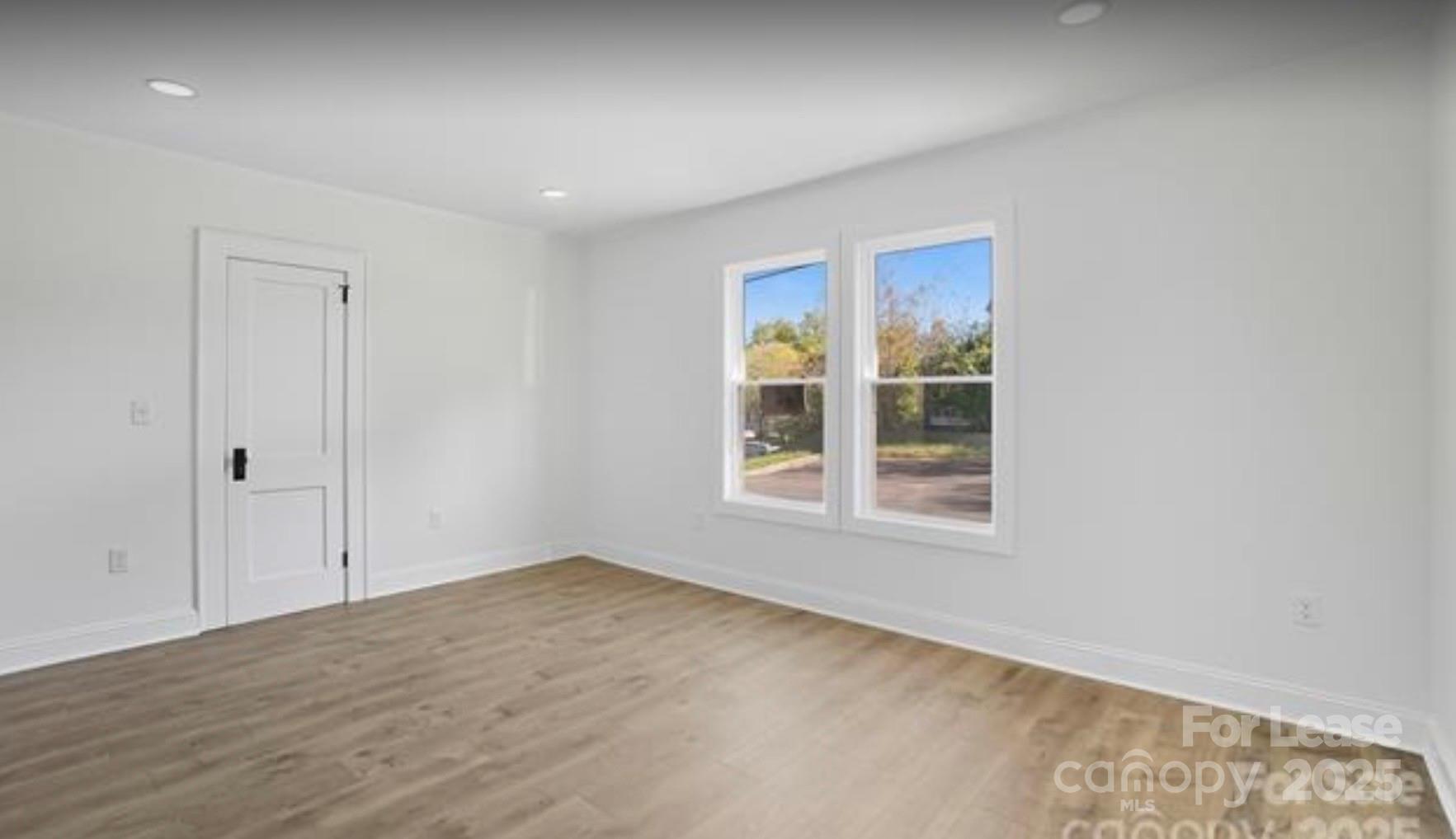 64 Brumley Avenue Northeast Concord, NC 28025 - Photo 11 of 19 an empty room with wooden floor and windows