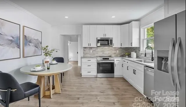 a kitchen with stainless steel appliances a stove a sink a microwave a refrigerator and a table