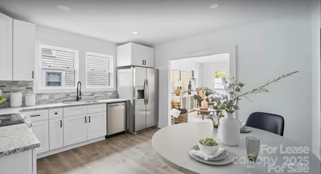 a kitchen with stainless steel appliances granite countertop a refrigerator a sink a stove and white cabinets