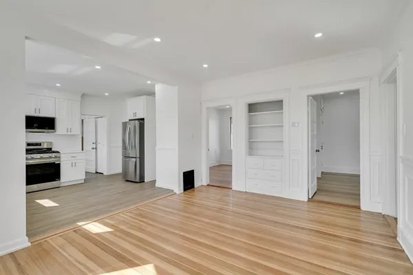 a view of a kitchen with refrigerator and an empty room