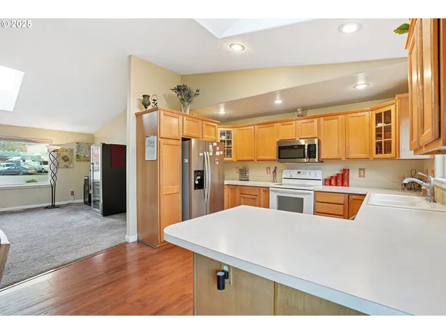 a kitchen with stainless steel appliances kitchen island granite countertop a refrigerator a stove top oven and a sink