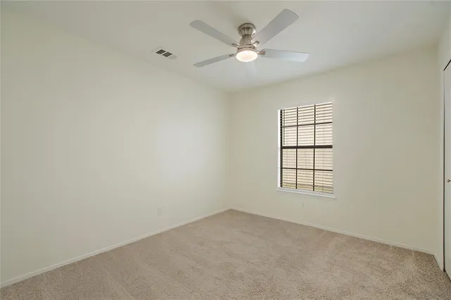an empty room with windows and ceiling fan