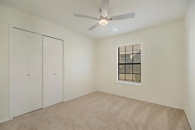 an empty room with windows and ceiling fan