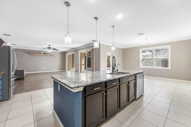 a large kitchen with stainless steel appliances kitchen island granite countertop a refrigerator and a stove top oven