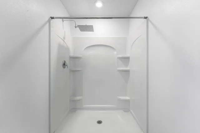 an empty room with wooden floor chandelier fan and windows