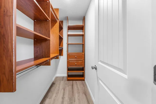 a view of an empty room with wooden floor and a ceiling fan