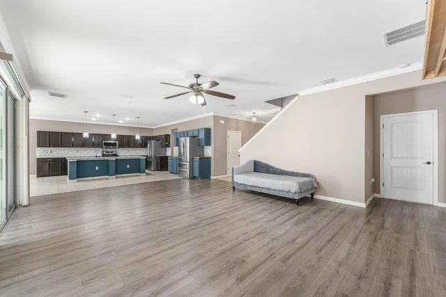 an empty room with wooden floor chandelier entryway and windows