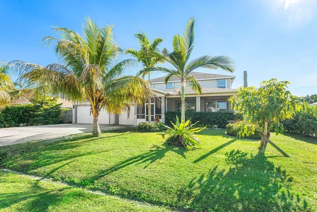 a view of a house with a big yard and palm trees