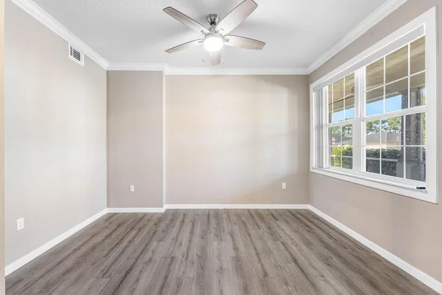 a view of an empty room with a window and wooden floor