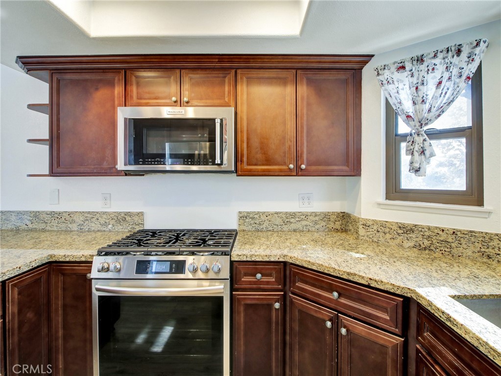 9051 Cobblestone Lane, Unit 40 Cypress, CA 90630 - Photo 17 of 38 a kitchen with granite countertop a stove top oven sink and cabinets