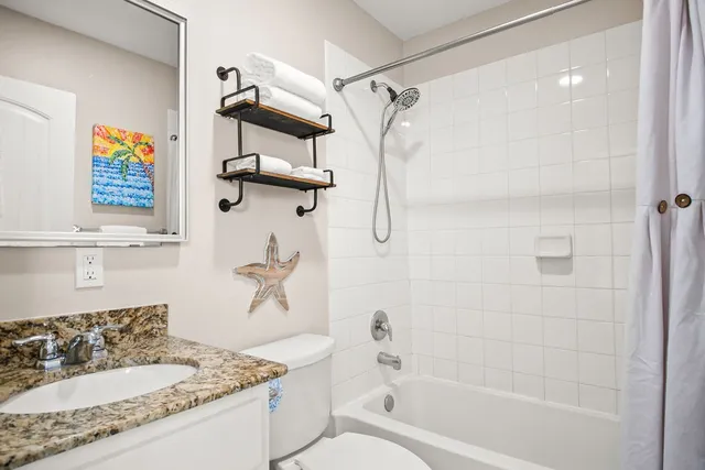 a bathroom with a granite countertop bathtub sink vanity mirror and toilet