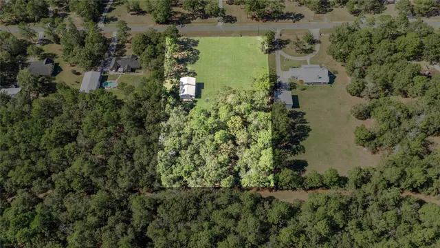 an aerial view of ocean with residential house with trees all around