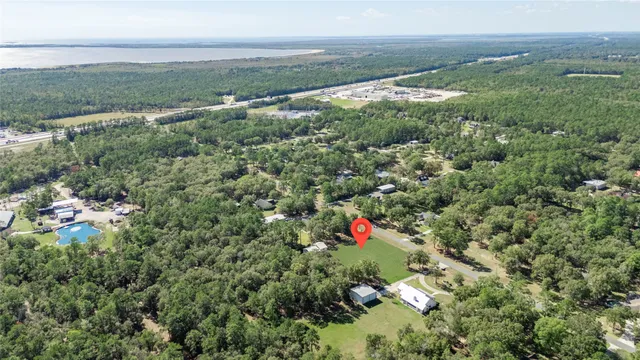 a view of a field with an ocean and trees in the background