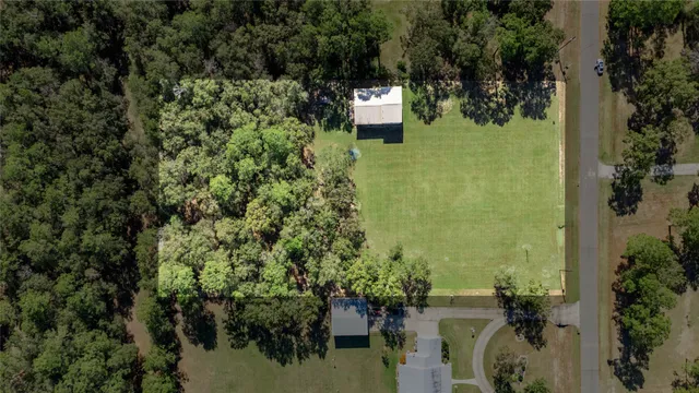 an aerial view of residential house with outdoor space and trees all around