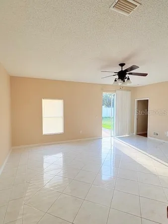 en empty room with windows and ceiling fan