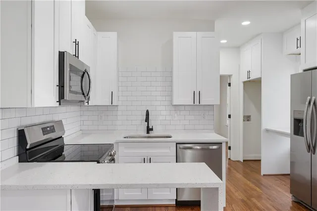 a kitchen with stainless steel appliances a refrigerator a sink a stove and white cabinets