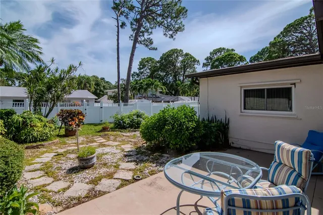 a backyard of a house with table and chairs plants