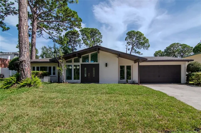 a front view of a house with a garden and trees