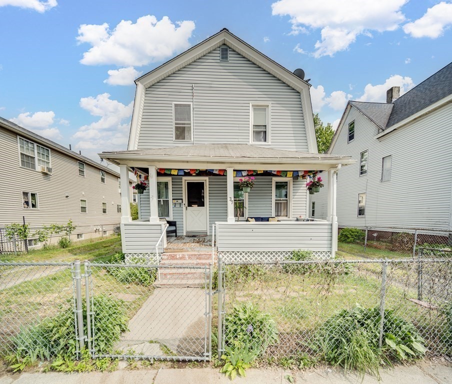 a view of house that has a small yard plants and large tree