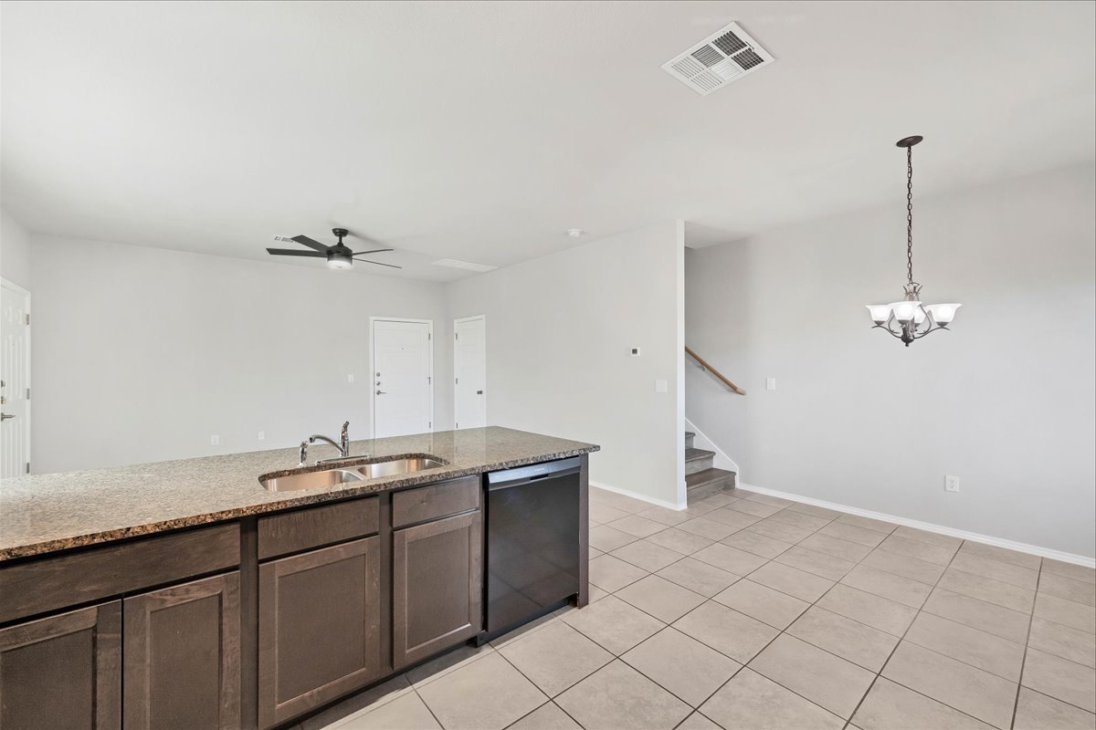 1202 Garland Road Georgetown, TX 78626 - Photo 14 of 28 Kitchen island featuring a stainless steel sink, granite-finish countertop, and dark wood-finish cabinetry