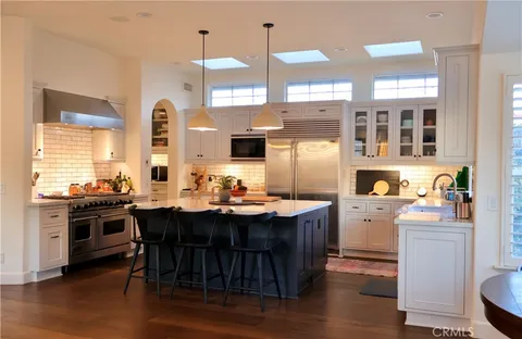 a kitchen with stainless steel appliances kitchen island granite countertop a stove a sink dishwasher and a refrigerator with wooden floor