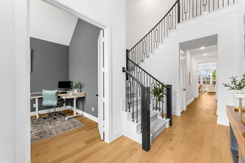 a view of a hallway to a livingroom with wooden floor and furniture