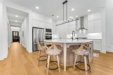 a kitchen with stainless steel appliances kitchen island granite countertop a dining table chairs and sink