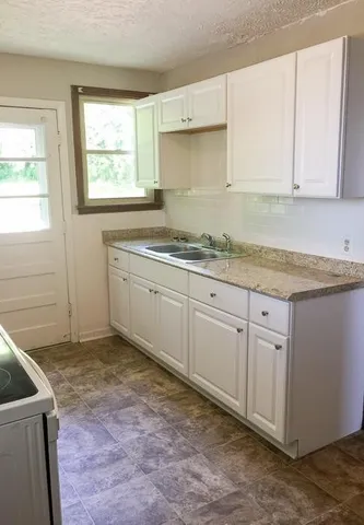 a kitchen with granite countertop a sink a stove and cabinets