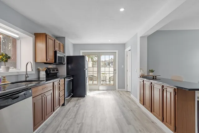 a kitchen with stainless steel appliances granite countertop a stove top oven a sink dishwasher a refrigerator and cabinets with wooden floor