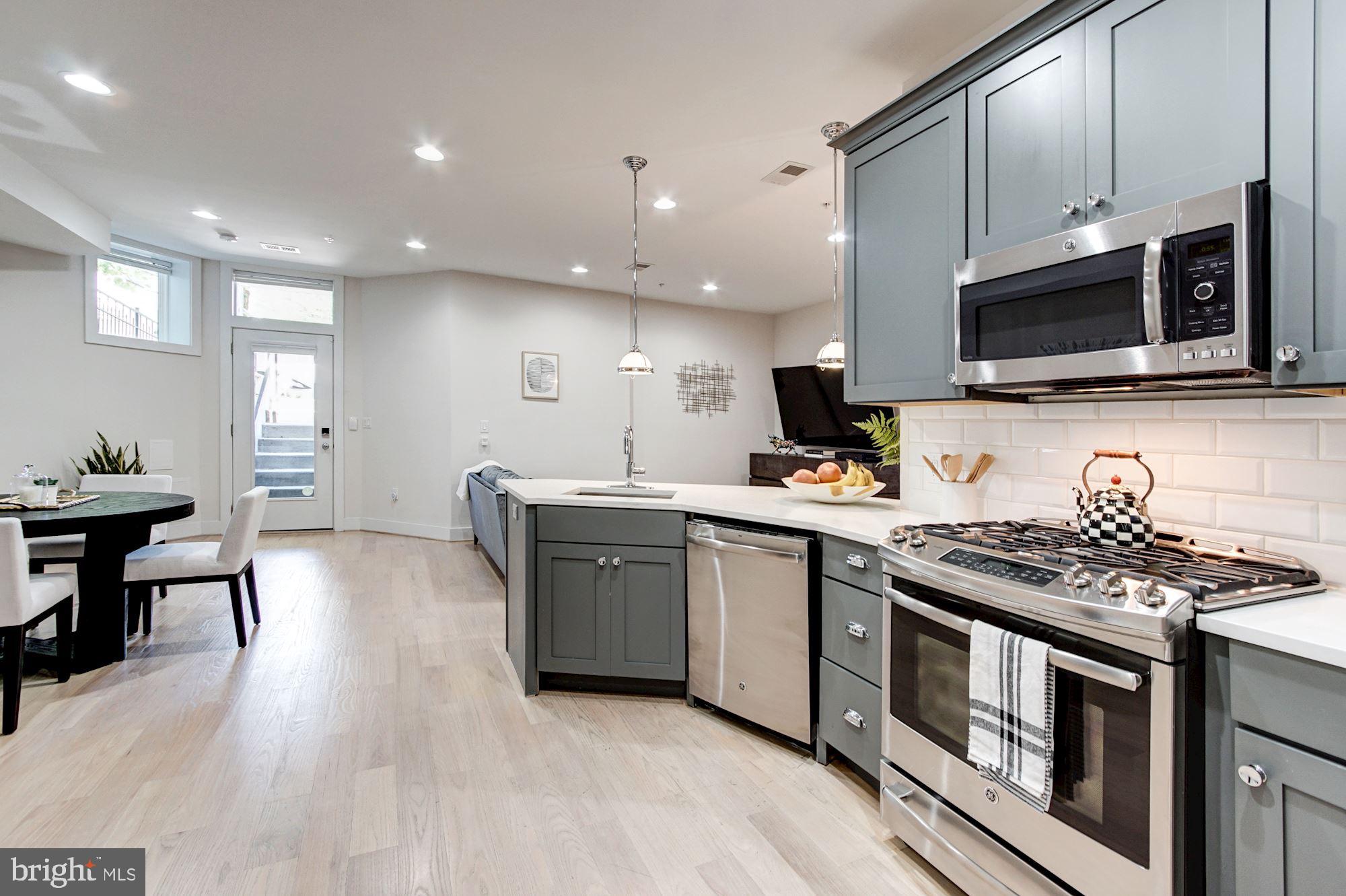 1352 Quincy Street Northwest, Unit 1 Washington, DC 20011 - Photo 8 of 26 a kitchen with stainless steel appliances kitchen island granite countertop a stove a sink and a microwave