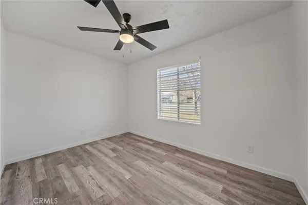 an empty room with ceiling fan and windows