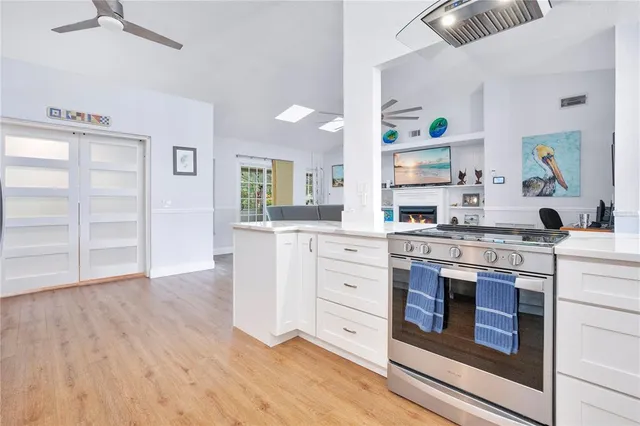 a kitchen with stainless steel appliances granite countertop a stove and white cabinets with wooden floor