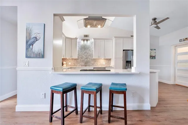 a kitchen with stainless steel appliances granite countertop a table chairs in it and wooden floor