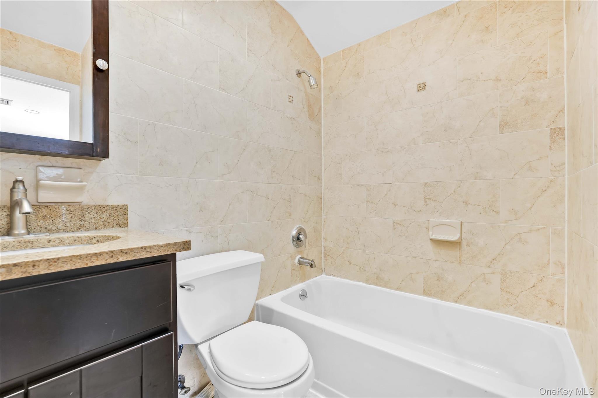 88-20 70th Road Queens, NY 11375 - Photo 30 of 31 a bathroom with a granite countertop toilet a sink a mirror and bathtub