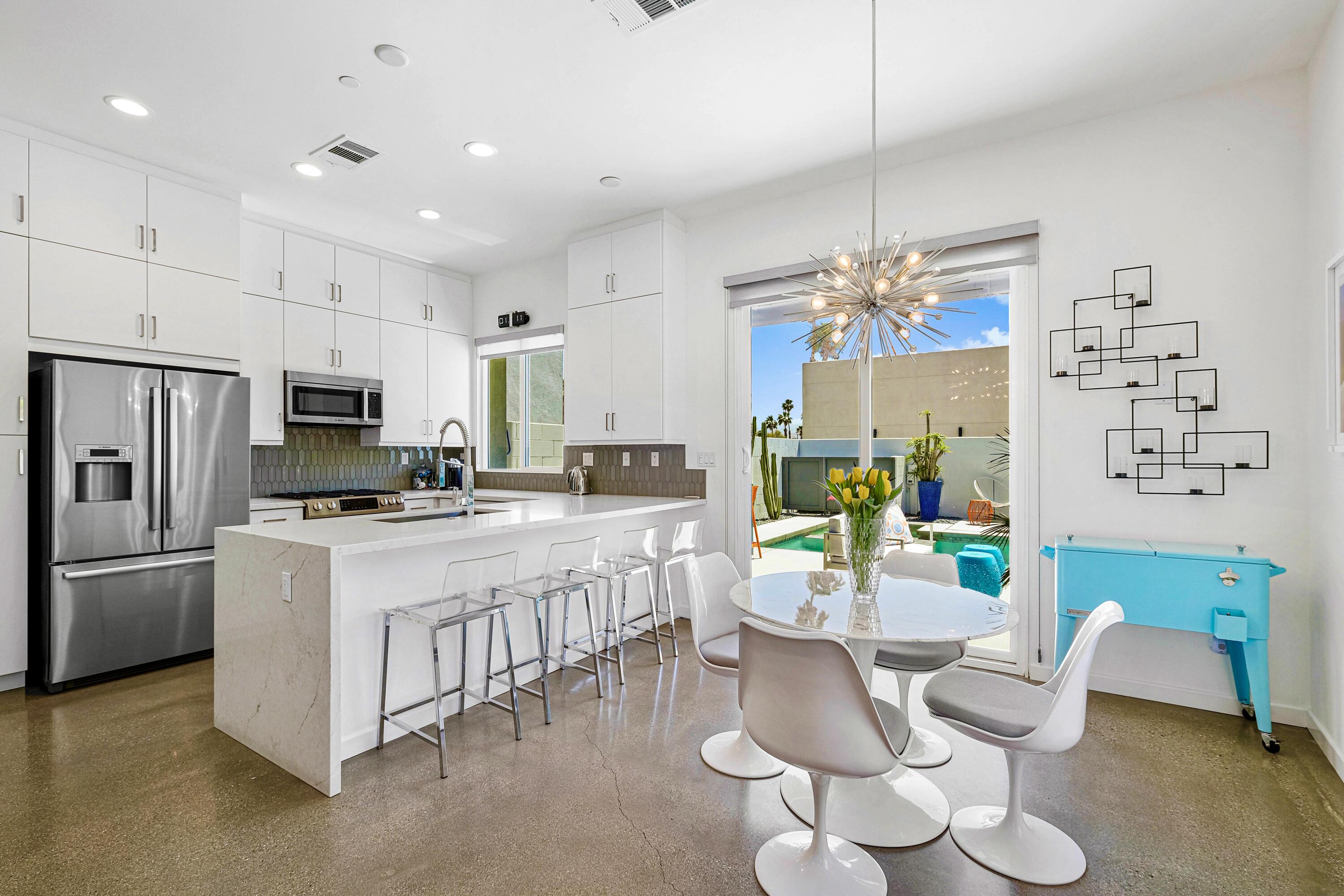 489 Beacon Way Palm Springs, CA 92262 - Photo 19 of 35 a kitchen with stainless steel appliances kitchen island granite countertop a refrigerator a stove top oven a sink dishwasher and a dining table with the view of kitchen