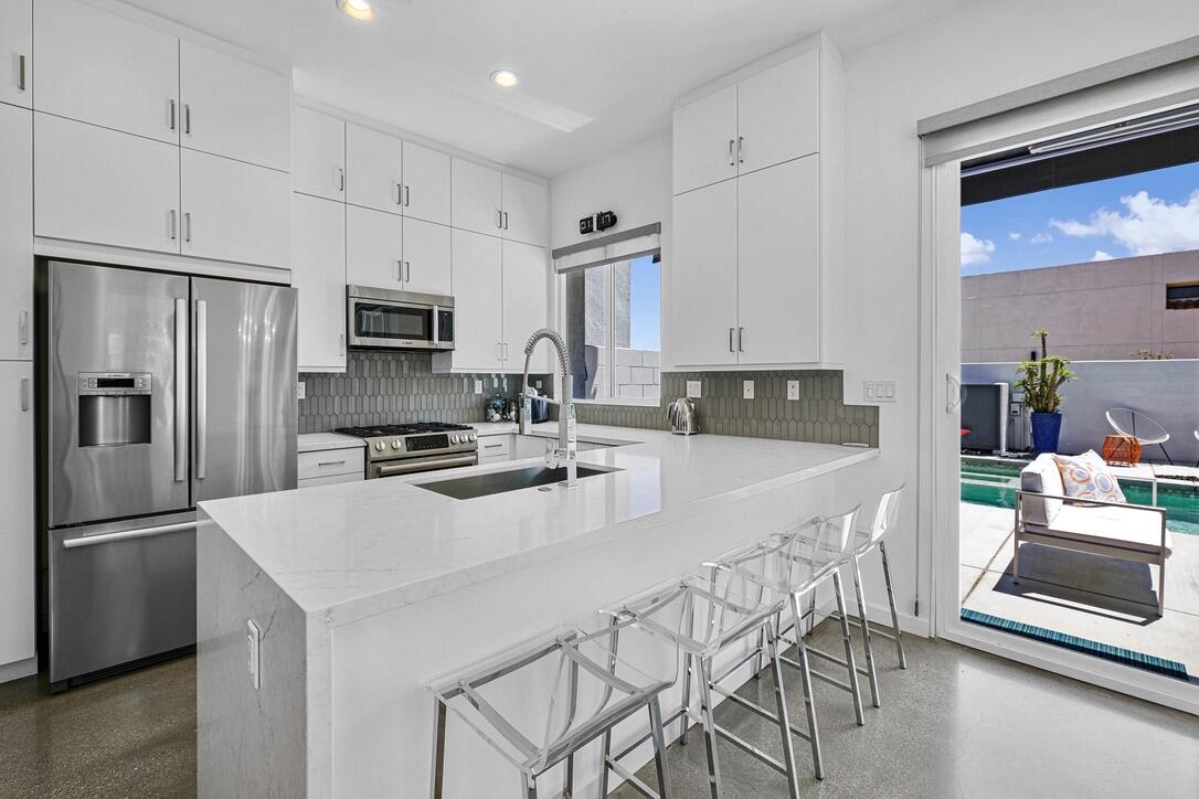 489 Beacon Way Palm Springs, CA 92262 - Photo 20 of 35 a kitchen with granite countertop a refrigerator a stove a sink a counter space and cabinets