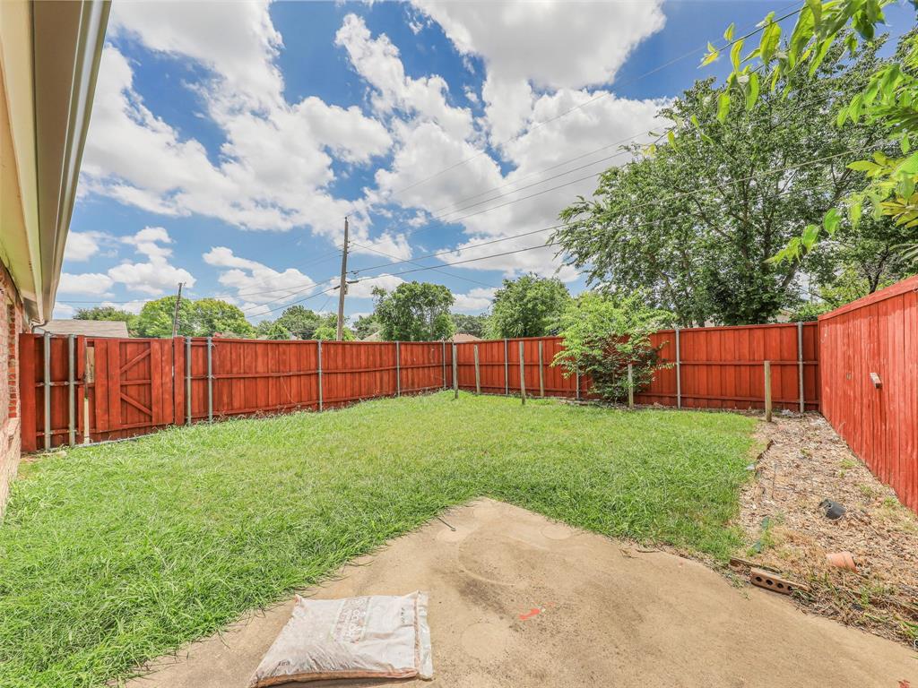 1716 East Parker Road Plano, TX 75074 - Photo 24 of 25 Expansive backyard featuring a red-stained wooden privacy fence, mature trees, and an established lawn