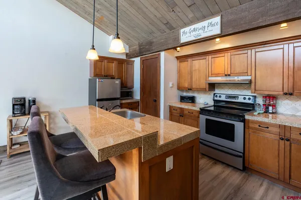 a kitchen with stainless steel appliances kitchen island granite countertop a stove a sink and a refrigerator