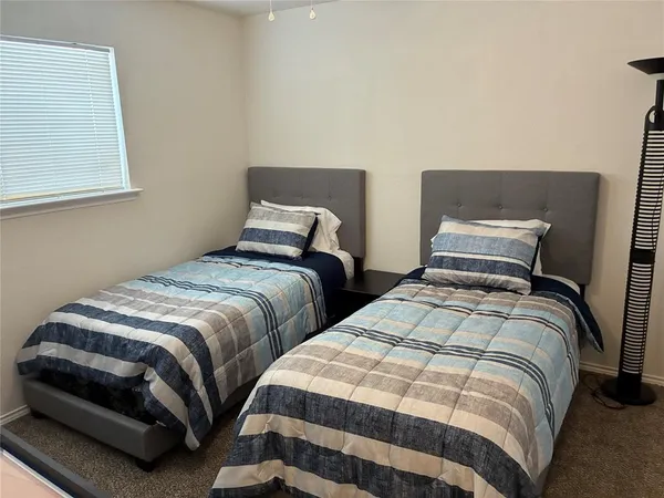 a bedroom with two beds and a lamp on dresser