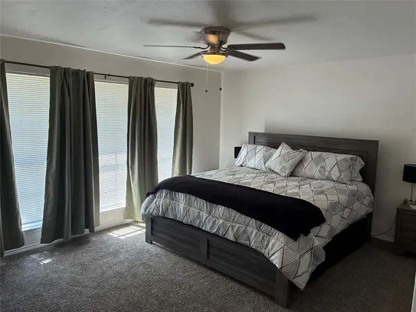 a bedroom with a bed lamp and a large window