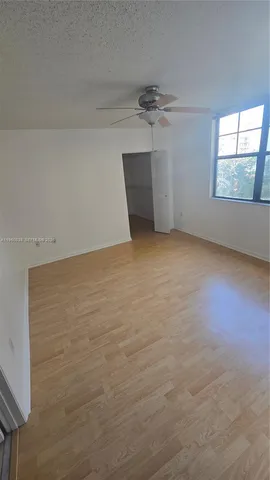an empty room with windows and fan