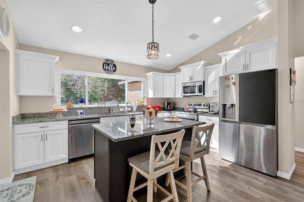 18168 Southwest 65th Loop Dunnellon, FL 34432 - Photo 10 of 26 a kitchen with stainless steel appliances kitchen island granite countertop a sink a stove a refrigerator and island with wooden floor