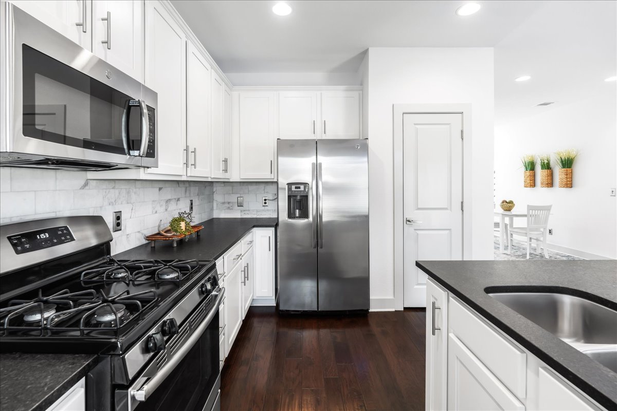 2021 Local Rebel Street, Unit 2021 Leander, TX 78641 - Photo 11 of 40 Kitchen with appliances with stainless steel finishes, dark wood-type flooring, backsplash, white cabinetry, and recessed lighting