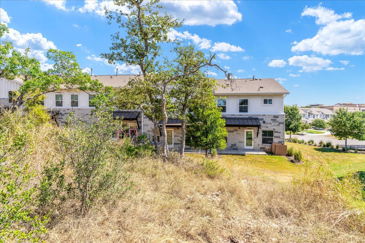 2021 Local Rebel Street, Unit 2021 Leander, TX 78641 - Photo 32 of 40 Back of property featuring a patio, a standing seam roof, a metal roof, stone siding, and a residential view