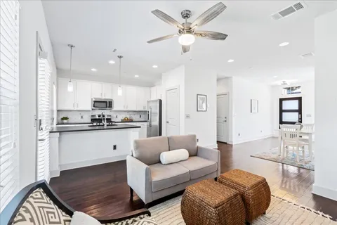 a living room with furniture kitchen view and a chandelier