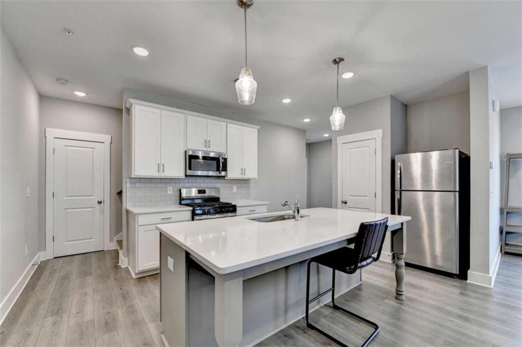 1714 Prospect Way Conyers, GA 30094 - Photo 10 of 35 a kitchen with stainless steel appliances a dining table chairs refrigerator sink and cabinets