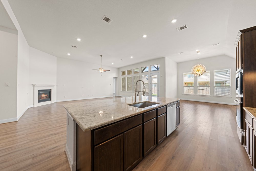 4208 Brean Down Road Pflugerville, TX 78660 - Photo 31 of 31 An open floor plan connects the kitchen, dining space, and living area with wood flooring.