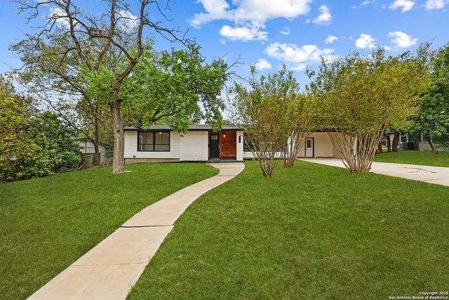 a front view of a house with a yard and trees